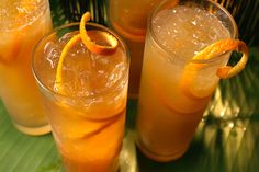 three glasses filled with orange juice and garnished with an orange slice