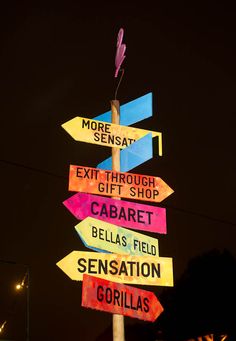 a pole with many different colored signs on it's side in front of a building