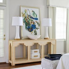 a white bed sitting next to a wooden table with two lamps on top of it