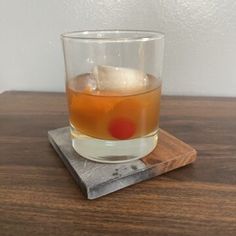 a glass filled with liquid sitting on top of a wooden table