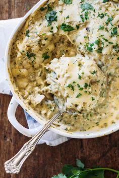 a white bowl filled with broccoli and cheese covered in gravy on top of a wooden table