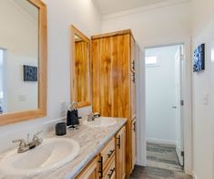 a bathroom with double sinks and wooden cabinets