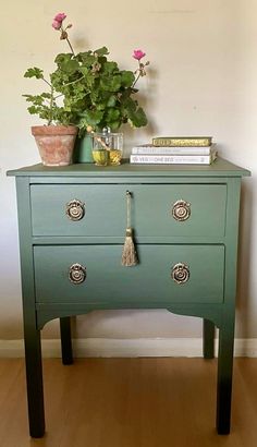 a green dresser with flowers and books on top