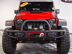 a red jeep parked in a garage with a sign on it's front bumper