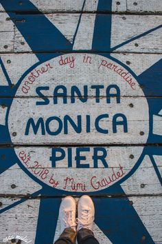 a person standing in front of a sign that says santa monica pier