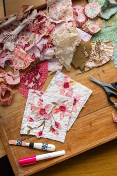 many pieces of fabric are laid out on a table with scissors and other crafting supplies