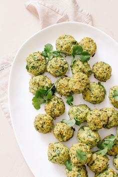 a white plate topped with broccoli covered in cheese and cilantro leaves