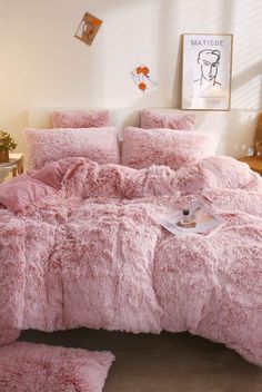 a bed covered in pink fluffy blankets and pillows