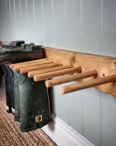 a coat rack made out of wood and hanging on the wall next to a pair of boots