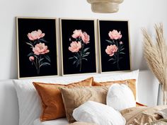 three framed flowers are displayed on the wall above a bed with white sheets and pillows