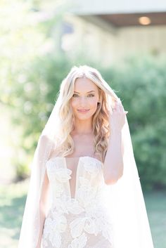 a woman in a wedding dress and veil posing for the camera with her hand on her head