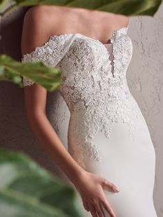 a woman in a wedding dress standing next to a plant