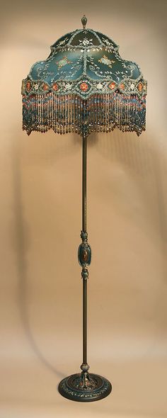 an antique lamp with beaded shades on it's base and a blue shade