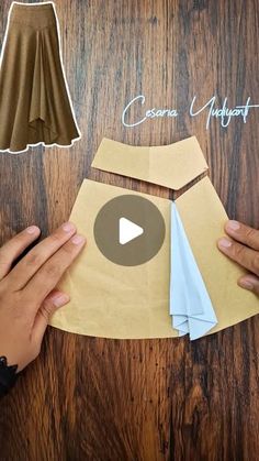 someone is making a paper skirt out of brown paper on a wooden table with scissors