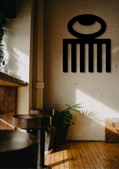 a white brick wall with a black metal sign on it and some plants in the corner