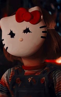 a hello kitty doll with a red bow on her head in front of some candles