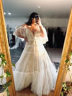 a woman taking a selfie in front of a mirror wearing a wedding dress with ruffles