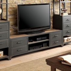 a large flat screen tv sitting on top of a wooden entertainment center next to a brick wall