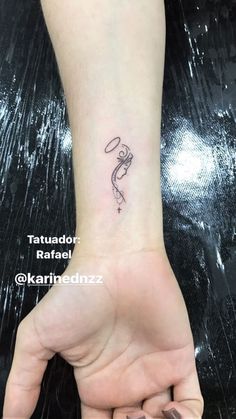 a woman's hand with a small tattoo on the wrist and an outline of a snake