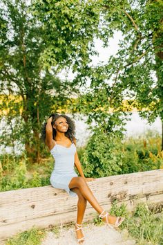 a woman sitting on top of a wooden fence