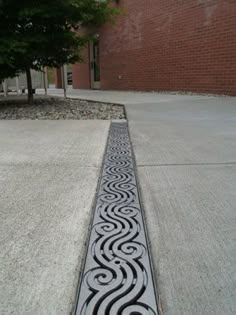 a black and white design on the ground in front of a brick building with trees