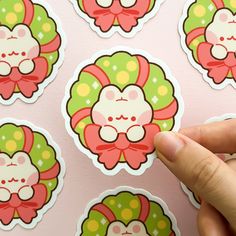 a hand is pointing at some stickers on a pink wall with green and red designs