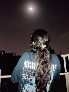 a woman with long hair looking at the moon