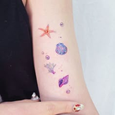 a woman's arm with tattoos on it that include shells and starfishs