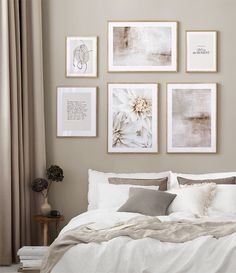 a bed with white sheets and pillows in front of pictures on the wall above it