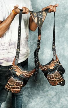 a man is holding two leather bags with chains on them, and the straps are attached to each other