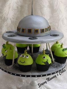 cupcakes in the shape of alien heads on top of a cake