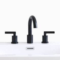 two black faucets sitting on top of a white sink