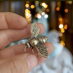 a tiny gold bee sitting on top of someone's finger