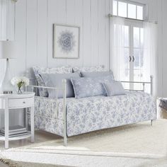 a white and blue bedroom with a daybed in the corner next to a window