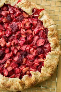 a pie with strawberries on it sitting on a cooling rack