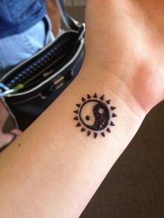 a small tattoo on the wrist of a person with a black and white yin - yang symbol