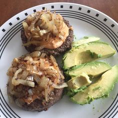 an avocado and two hamburgers on a plate with some sort of topping