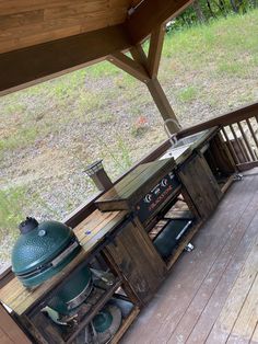 an outdoor grill on a deck in the middle of a field with grass and trees