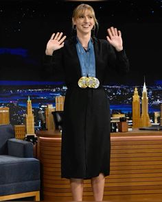 a woman standing in front of a table with her hands up and wearing a black dress