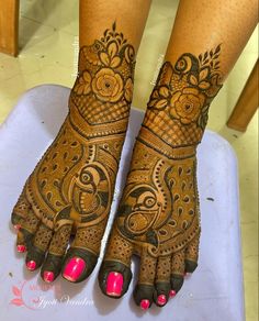 two feet with henna tattoos on them and pink nail polishes in the foreground