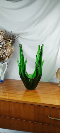 a green vase sitting on top of a wooden dresser