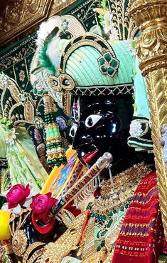 an elaborately decorated shrine with gold and red decorations on the walls, including a black mask