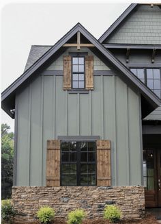 a large gray house with wooden shutters and windows