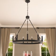 a chandelier hanging from the ceiling in a dining room with windows and curtains