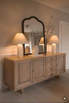 a dresser with two lamps and a mirror