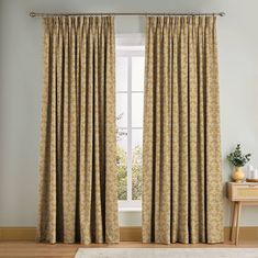 a living room with a large window covered in curtains and a rug on the floor