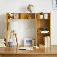 a wooden desk topped with a book shelf filled with lots of books next to a lamp