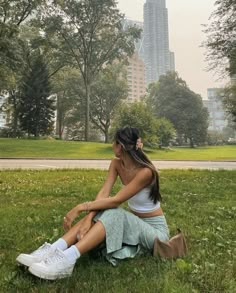 a woman sitting in the grass with her legs crossed