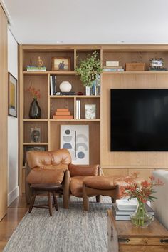 a living room filled with furniture and a flat screen tv mounted on a wooden wall