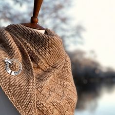 a knitted bag hanging from a hook on a clothes line next to a body of water